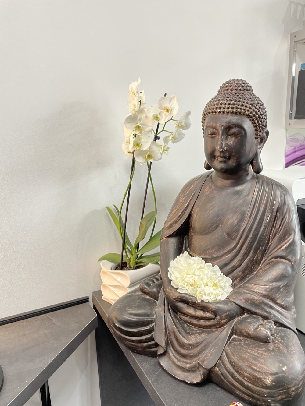 Buddha-Figur mit weißen Orchideen und Hortensie, ruhige Wohlfühl-Atmosphäre im Friseursalon Zerrin & Friseure in Berlin-Südende
